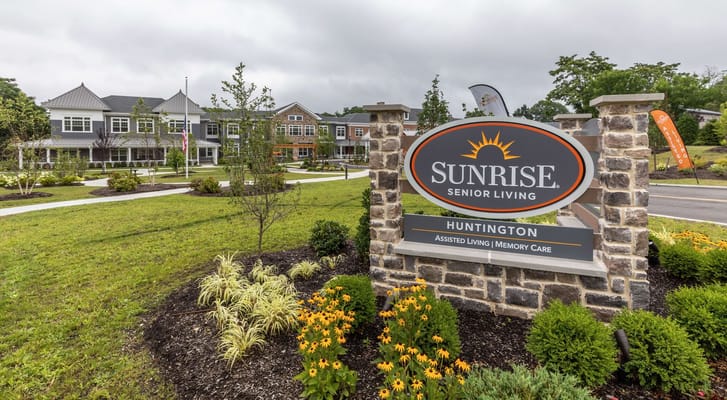 Sign for Sunrise Senior Living at Huntington with flowers and grass in front.