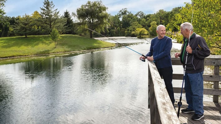 Two residents fishing on a serene pond
