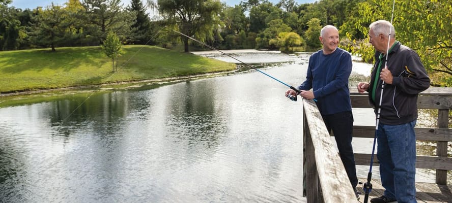 Two residents fishing by a serene pond