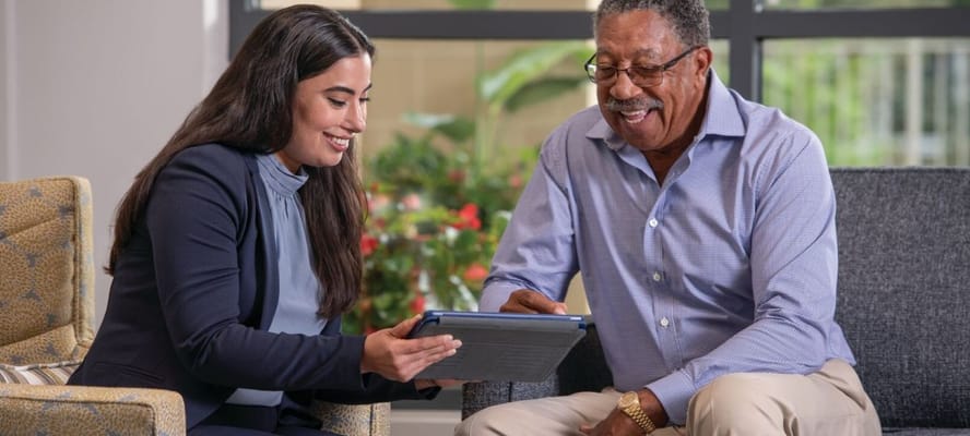 A staff member assisting a resident with a tablet