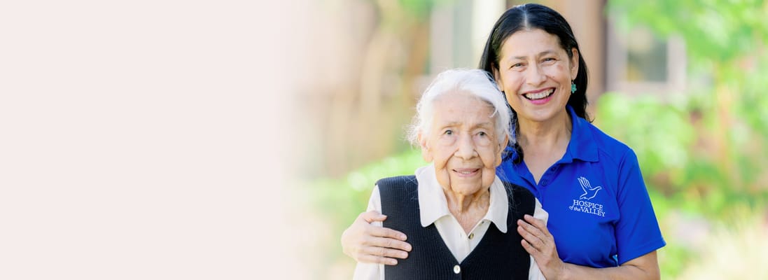 Caregiver and resident smiling in an outdoor space
