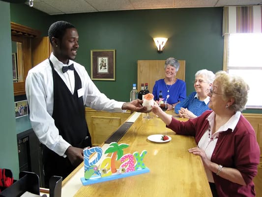 Staff serving refreshments to residents in a cozy setting