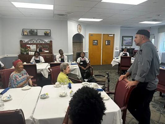 Residents engaged in conversation with staff in a dining room