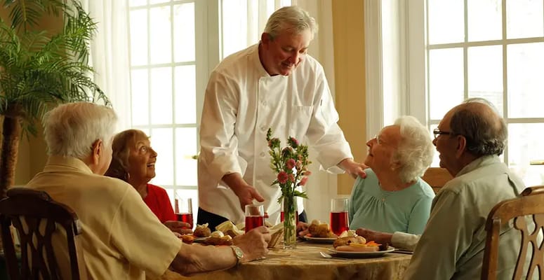 Residents enjoying a meal with staff in the dining room