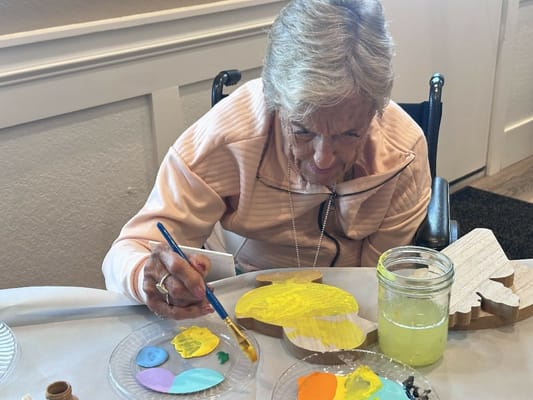 Resident painting a wooden craft in an activity room