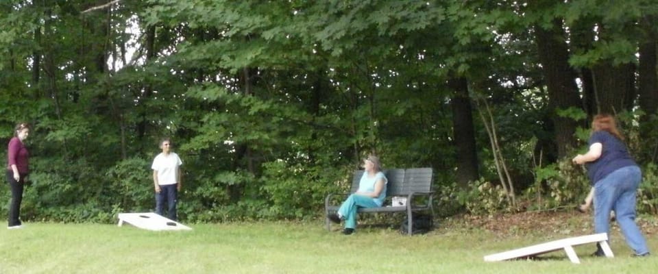 Residents participating in a cornhole game outdoors