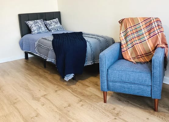 A cozy resident room with a bed and armchair