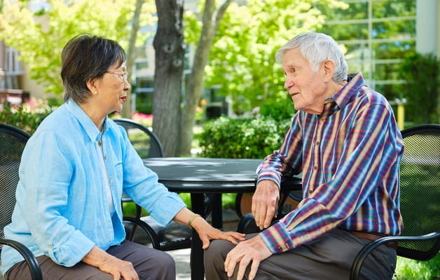 Two seniors conversing in a garden area