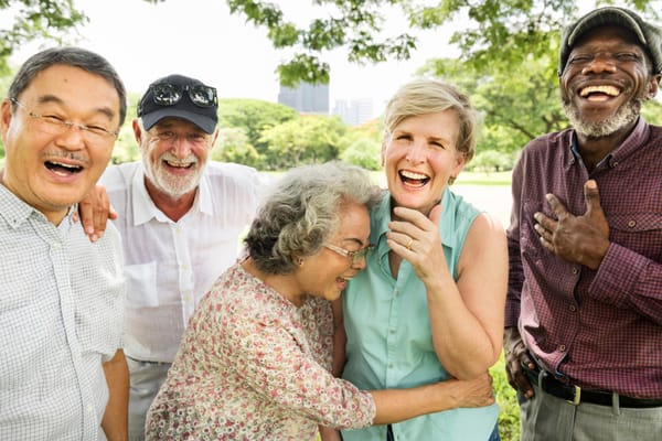 A diverse group of seniors laughing together outdoors