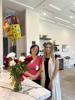 Staff and resident celebrating with flowers and balloons