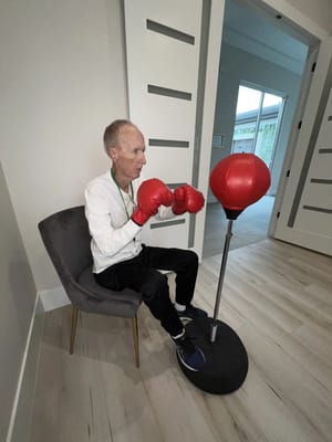 A resident boxing at a fitness station in a facility interior