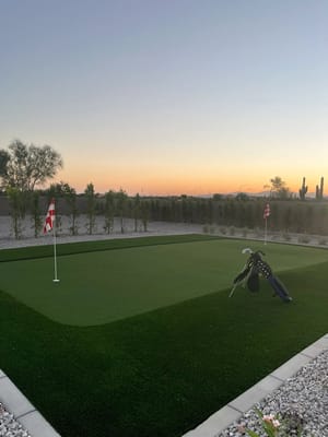 Outdoor putting green at sunset with golf clubs