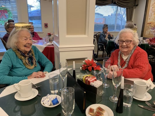 Two smiling residents having tea in the dining area