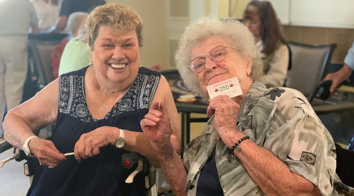 Two residents smiling and holding a prize in a common area