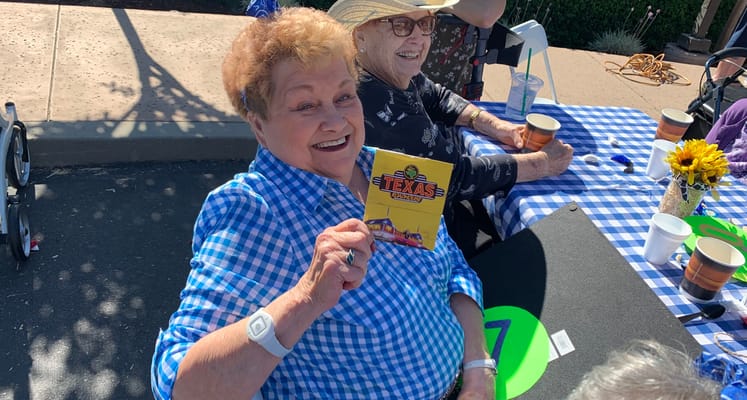 Resident enjoying an outdoor event with a prize card