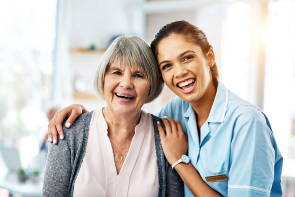 A smiling resident and staff member in a bright common area