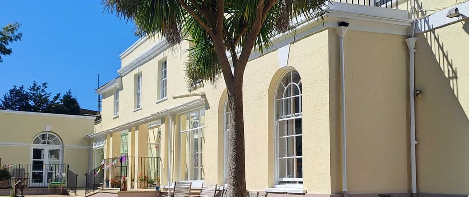 Exterior view of Arcot House Care Home with palm tree