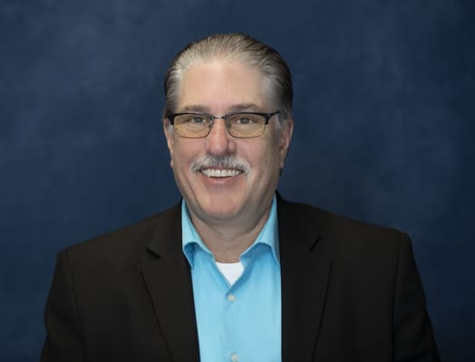 A staff member smiling against a blue background
