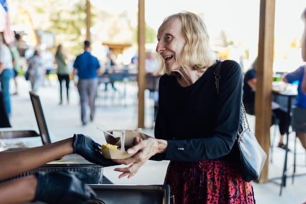 Resident enjoying food outdoors with staff assistance