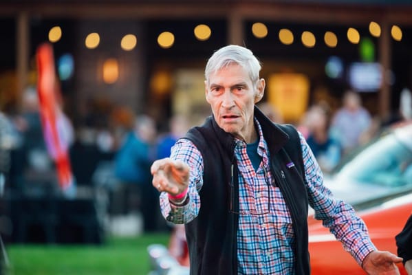An elderly man pointing at an outdoor event