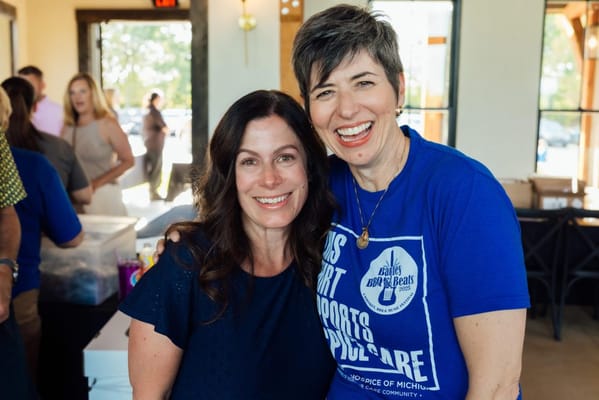 Two smiling women at an event in a common area