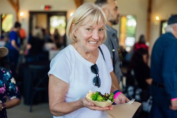 A smiling resident enjoying a salad in a social setting
