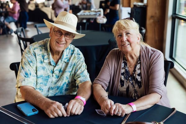 Two seniors smiling at a table in a social setting