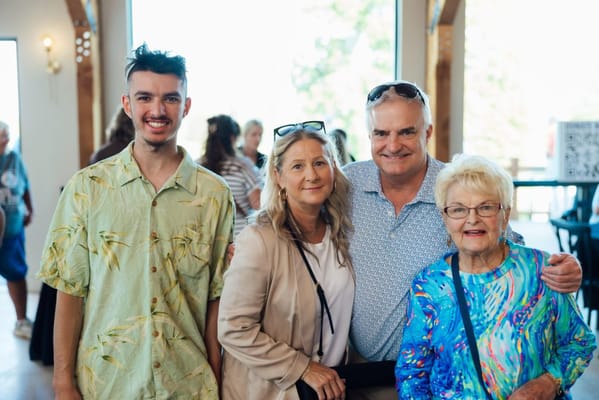 A group of four people smiling together in an indoor space