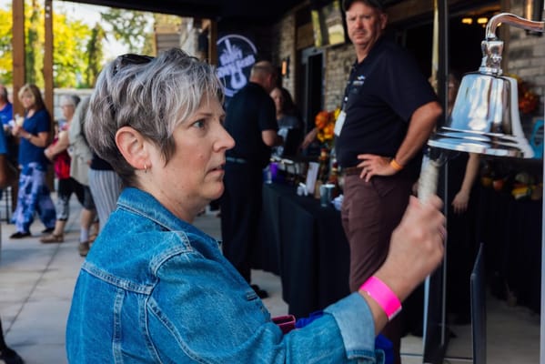 A woman ringing a bell at an event with people in the background