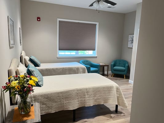 A cozy resident room with two beds and a bouquet