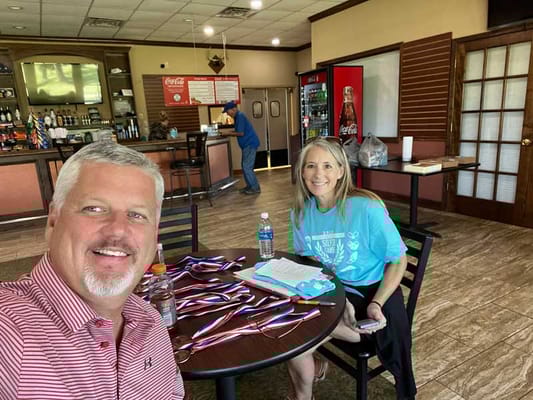 Two staff members in a dining area with awards