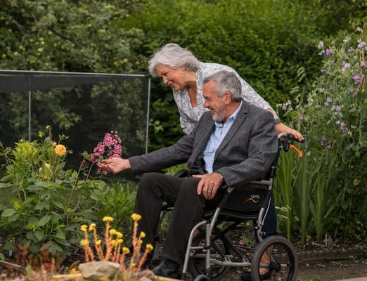 A resident enjoying gardening with staff assistance