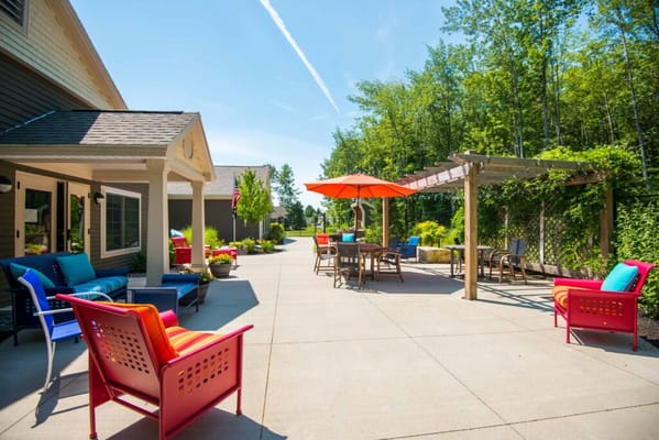 Colorful outdoor seating area with chairs, tables, and an umbrella.