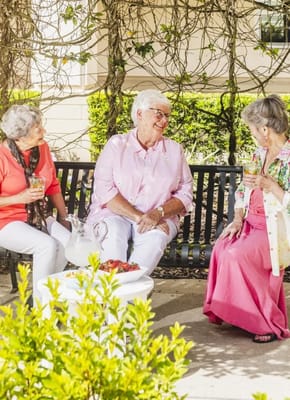 Three residents enjoying refreshments in a garden area