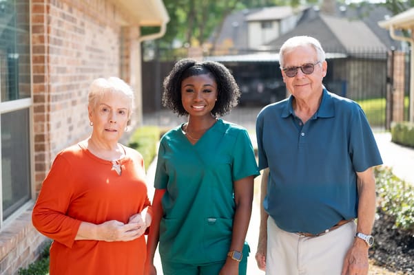 A caregiver with two residents in a garden pathway