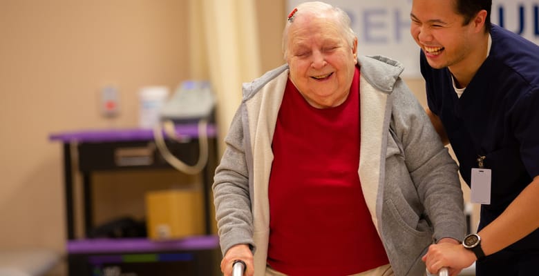 Resident walking with staff assistance in a supportive environment
