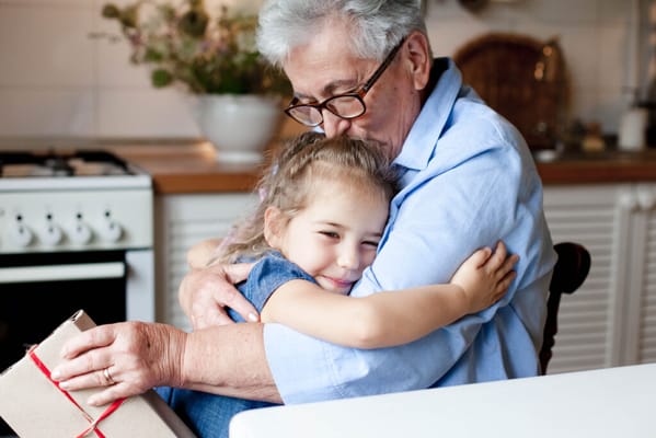An elderly person hugging a young child in a cozy kitchen