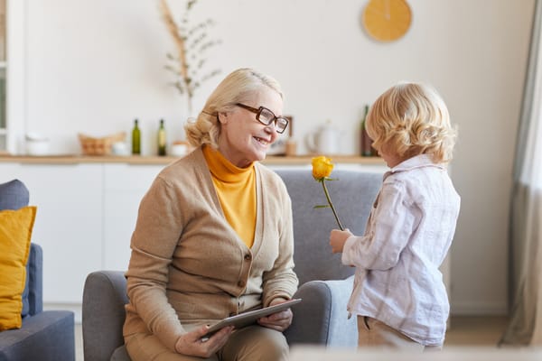 Senior resident smiling at a child with a flower
