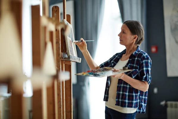 Resident painting at an easel in a bright activity room