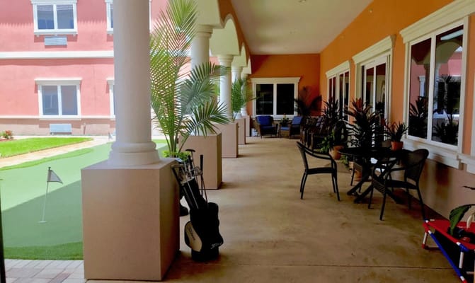 Covered outdoor patio area with seating and putting green
