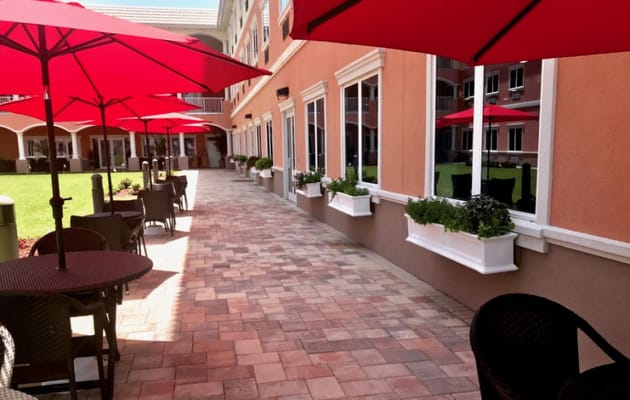 Outdoor seating area with red umbrellas and greenery