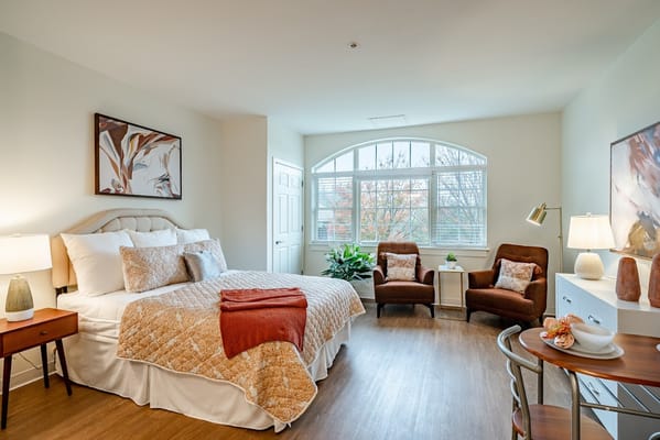 Bright and inviting bedroom with a large window and comfortable furnishings.