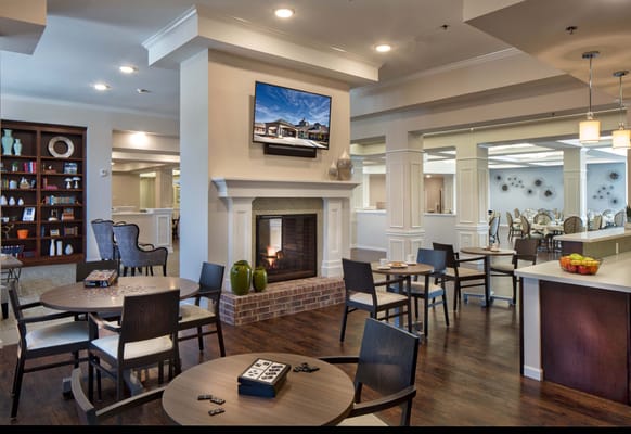 Cozy community lounge with tables, chairs, and a fireplace