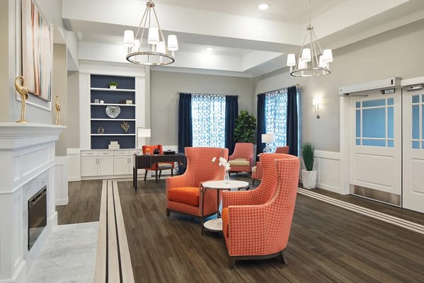 Bright and modern lobby with orange chairs and a desk.