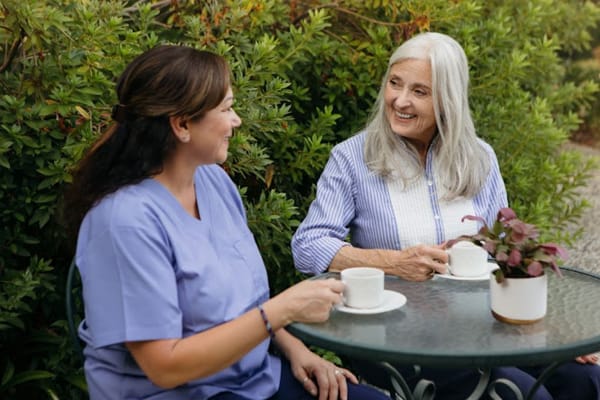 A caregiver sharing coffee with a resident in a garden