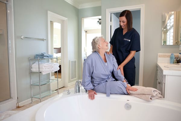 Caregiver assisting a senior woman in a bathroom setting