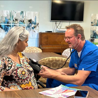 Staff member checking a resident's blood pressure in a common area