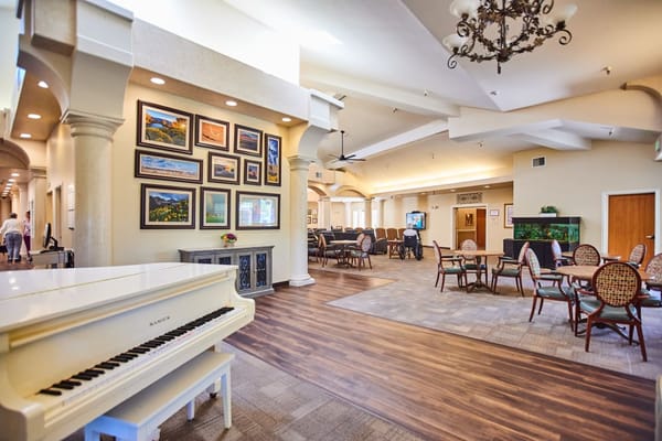 Bright common area with seating and a grand piano