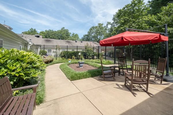 Seating area with rocking chairs and red umbrella in a garden