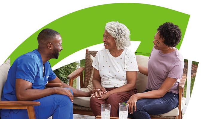 Supportive staff member engaging with senior residents outdoors.